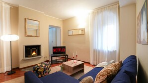 Un salon chaleureux avec une cheminée, un canapé, une table basse et un téléviseur affichant le logo « NETFLIX ».