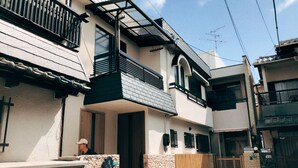 A two-story building with a balcony, a wooden door, and a small window. - HANASTAY YANAGI (Osaka)