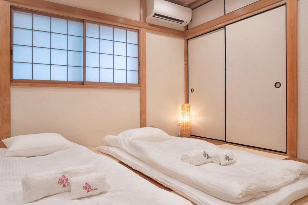 Ein traditioneller japanischer Raum mit Tatami-Boden, einer Schiebetür und einem Fenster mit Gittermuster.