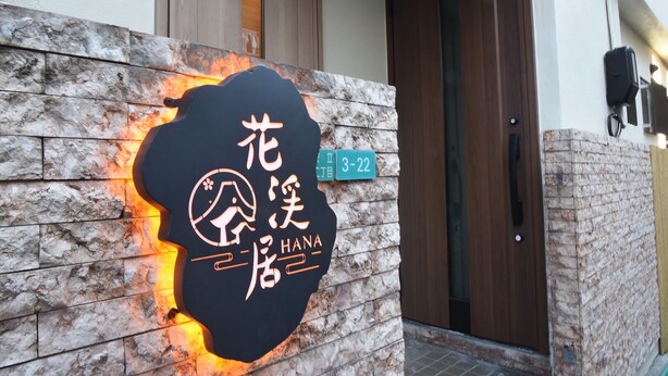 A building entrance with a stone wall and a sign with Chinese characters. - HANASTAY YANAGI (Osaka)