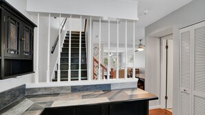 Una cocina moderna con una isla grande, barandales blancos y una escalera que sube a una zona estilo loft.