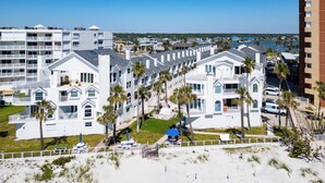 Un hotel costero con edificios de varios pisos, una zona de playa con palmeras y vistas al océano.