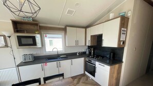 A modern kitchen with a microwave, toaster, sink, stove, and cabinets. - 3-Bed Caravan - Haven Lakeland Leisure Park (Grange-over-Sands)