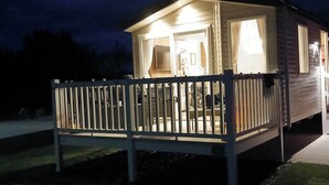 A small, single-story cabin with a porch and a fenced deck area. - 3-Bed Caravan - Haven Lakeland Leisure Park (Grange-over-Sands)