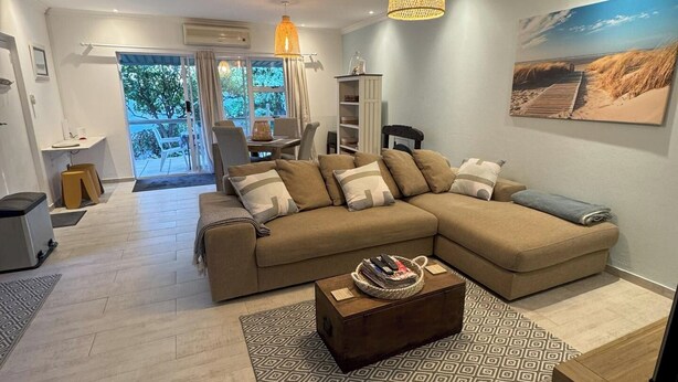 A modern living room with a large L-shaped sofa, a coffee table, and a dining area with a table and chairs.