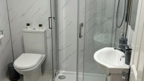 Une petite salle de bain comprenant des toilettes, une douche à parois de verre et un lavabo.