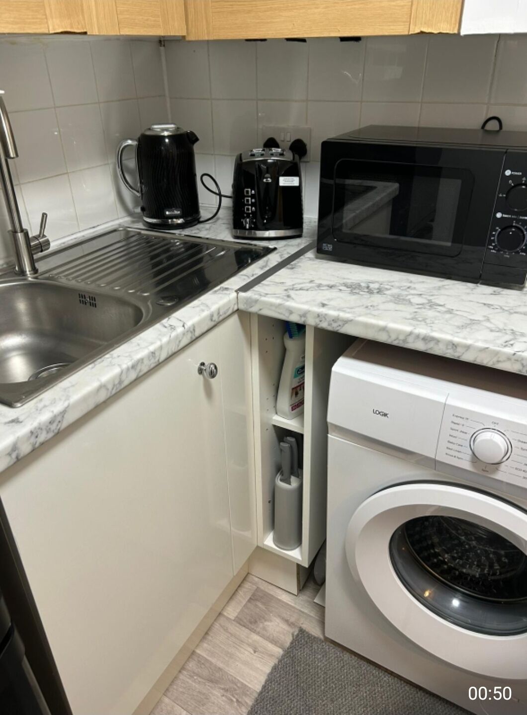 Una cucina compatta con lavandino, macchina da caffè, forno a microonde e lavatrice.