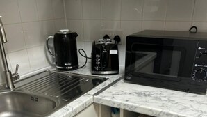 Une cuisine compacte équipée d’un évier, d’une machine à café, d’un four à micro-ondes et d’un lave-linge.