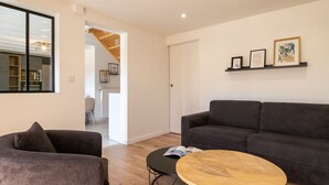 A modern living room with a grey sofa, a round wooden coffee table, and a bookshelf with framed pictures. - La Roselière by Interhome (Guissény)