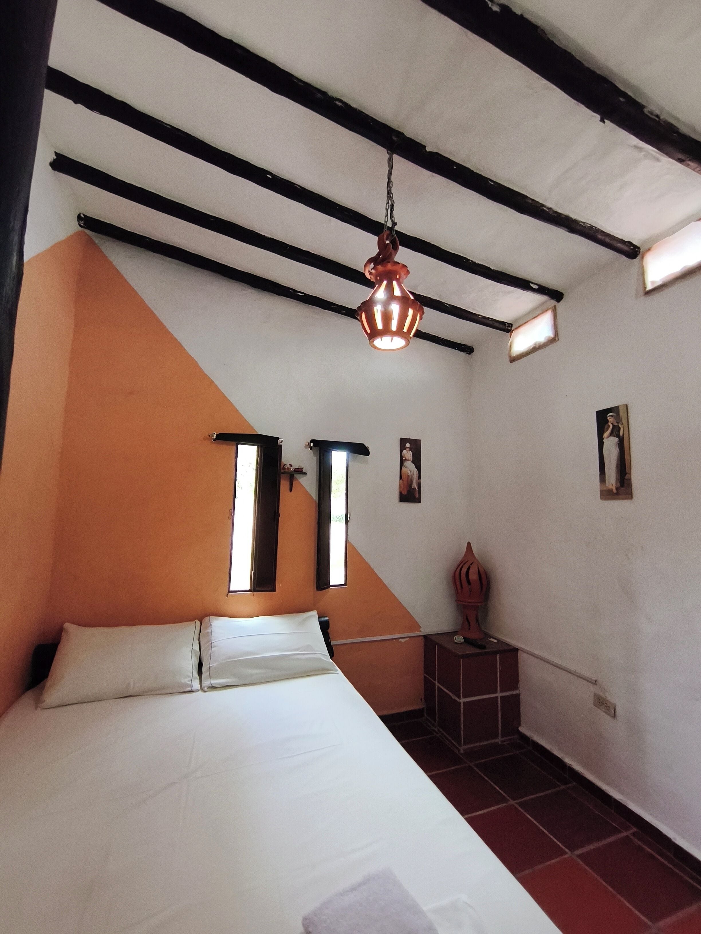 A room with a bed, a window, and a hanging light fixture.