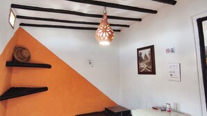 A room with a white ceiling, black beams, a hanging light fixture, a small white refrigerator, and a tiled floor. - Cabañas Cañón del Chicamocha (Aratoca)