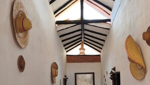 A hallway with a tiled floor, a ceiling with exposed beams, and wall-mounted hats. - Cabañas Cañón del Chicamocha (Aratoca)