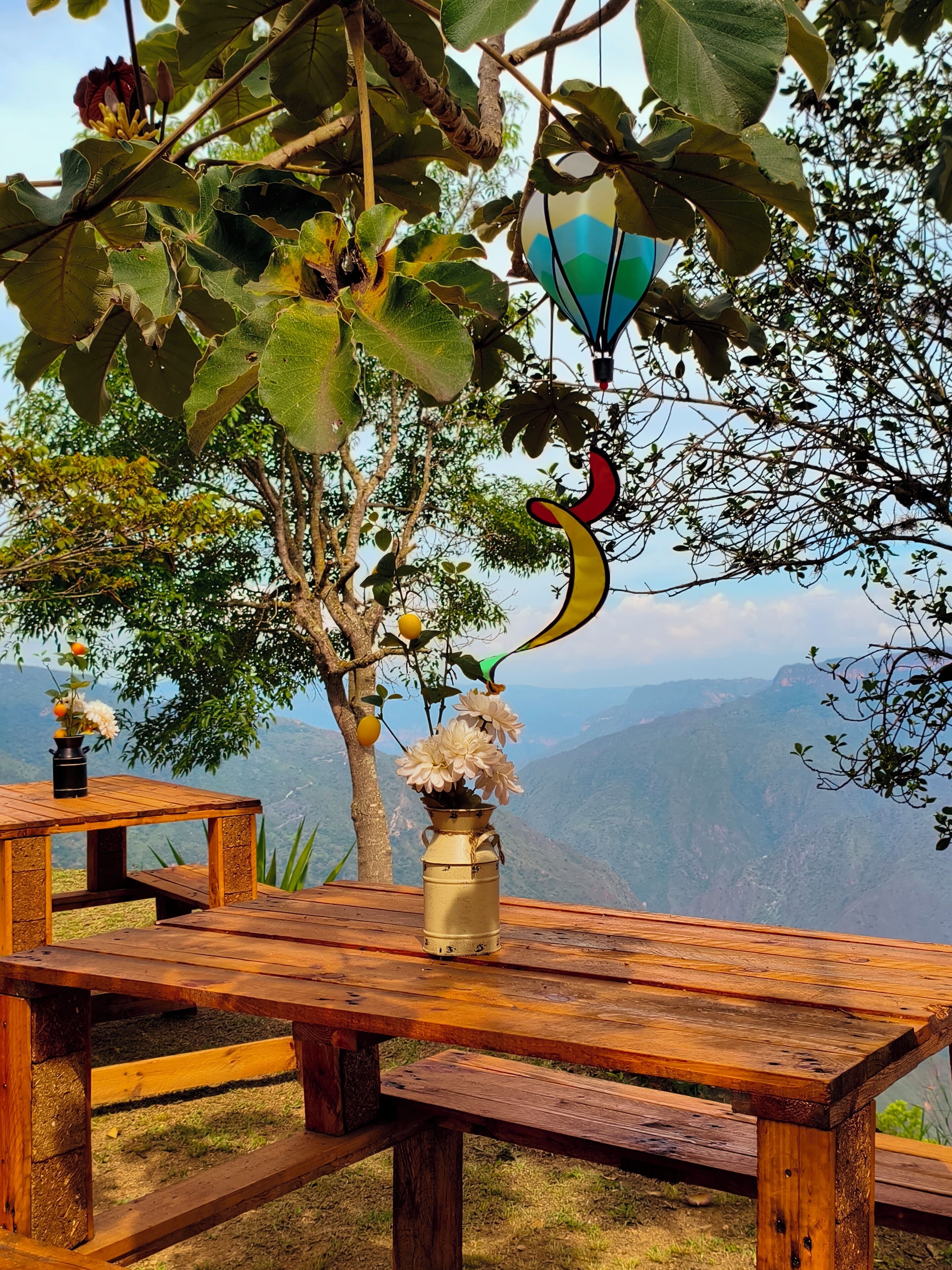Una mesa de picnic de madera con un jarrón de flores y una decoración de globo aerostático.