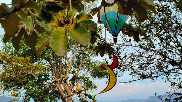 A wooden picnic table with a vase of flowers and a hot air balloon decoration. - Cabañas Cañón del Chicamocha (Aratoca)