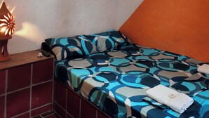 A bedroom with a bed, a hanging light fixture, and a wall with a geometric pattern. - Cabañas Cañón del Chicamocha (Aratoca)
