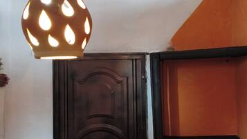 Una habitación con una puerta de madera oscura, una lámpara colgante con diseño de lágrima y una pared con motivo geométrico.