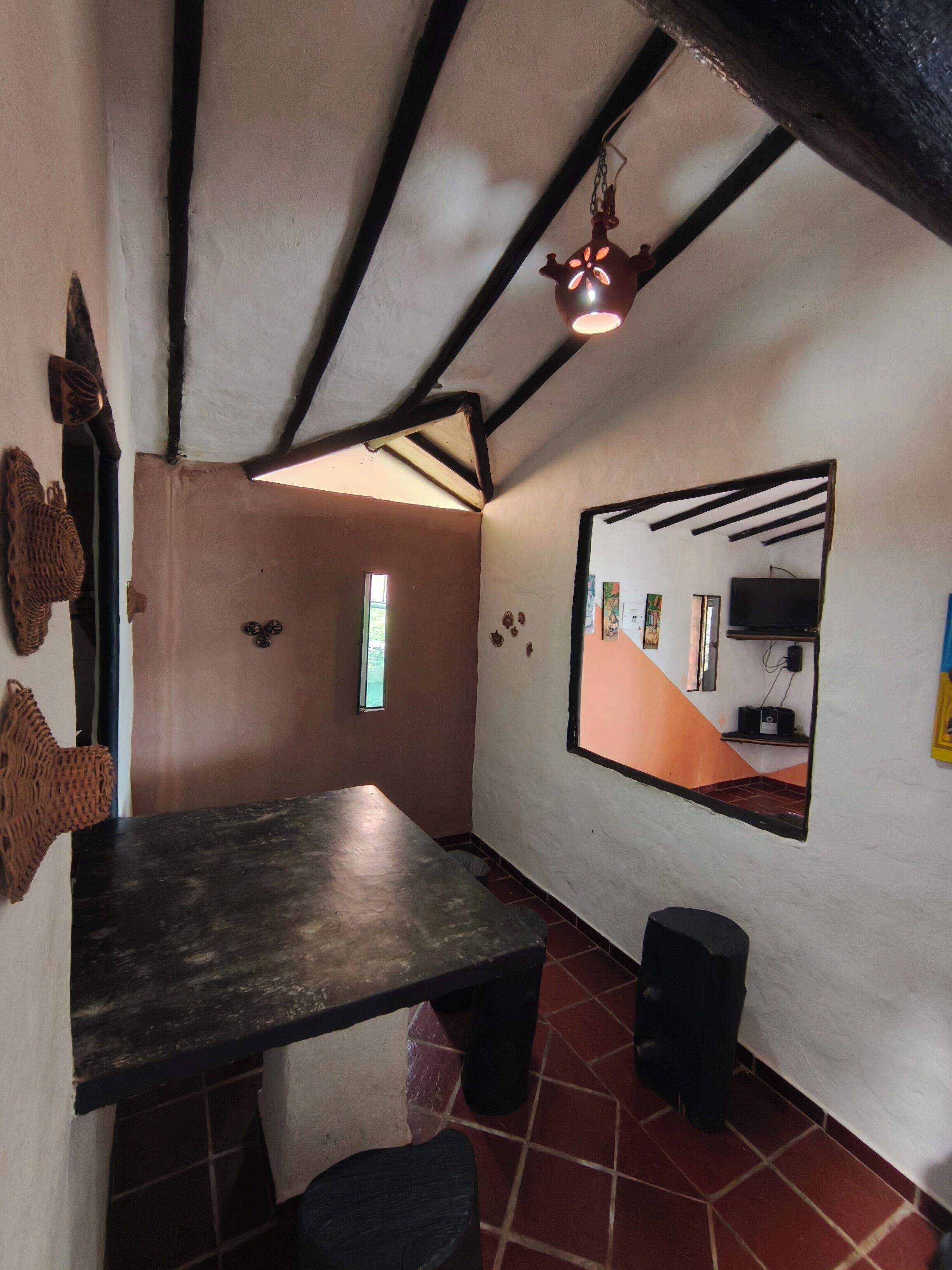 A room with a dark wooden table, a mirror on the wall, and a hanging light fixture.