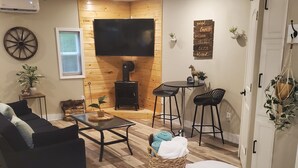 Een gezellige woonkamer met een bank, een salontafel, een televisie, een open haard en een eethoek met stoelen.