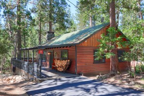 Un rustico chalet con tetto in metallo, veranda in legno e camino.