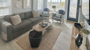 Un grand salon comprenant un canapé, des fauteuils, une table basse et un téléviseur.