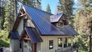 A two-story cabin with a metal roof, wooden beams, and a balcony.