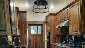 A kitchen with wooden cabinets, a marble countertop, and a central island with stools.