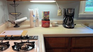 A kitchen with a gas stove, a coffee maker, and various kitchen items on the counter.