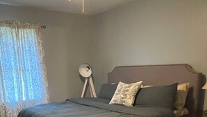A bedroom with a bed, a bedside table, a lamp, and a window with curtains.