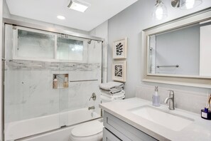 A modern bathroom with a glass-enclosed shower, a white sink, and a large mirror.