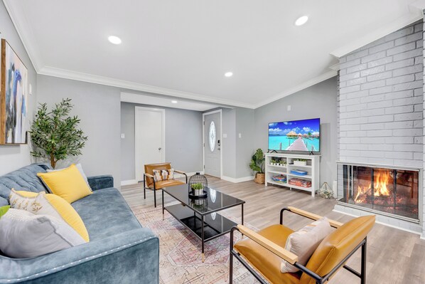 A modern living room with a grey sofa, a coffee table, a fireplace, and a television.