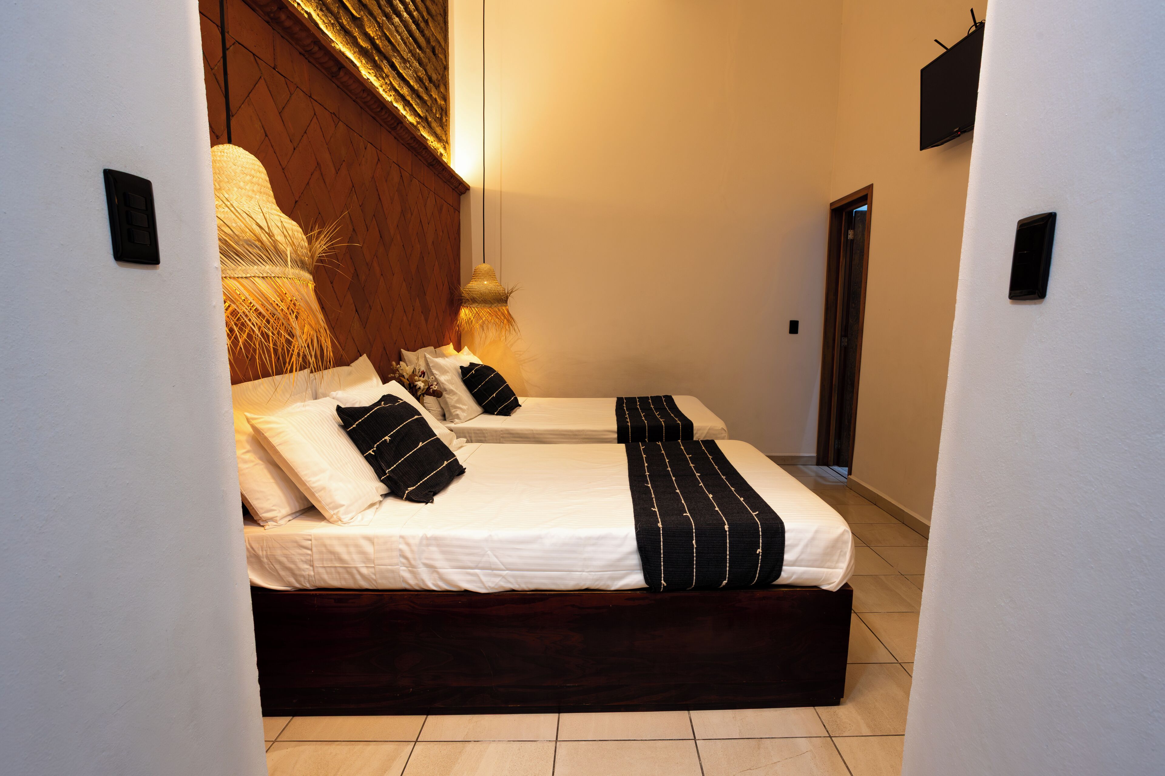 Una cama doble con cabecera de madera, ropa de cama blanca y almohadas decorativas a rayas.