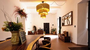 A dining area with a wooden table, chairs, a hanging light fixture, and decorative plants. - Casa Sofi Oaxaca (Oaxaca)