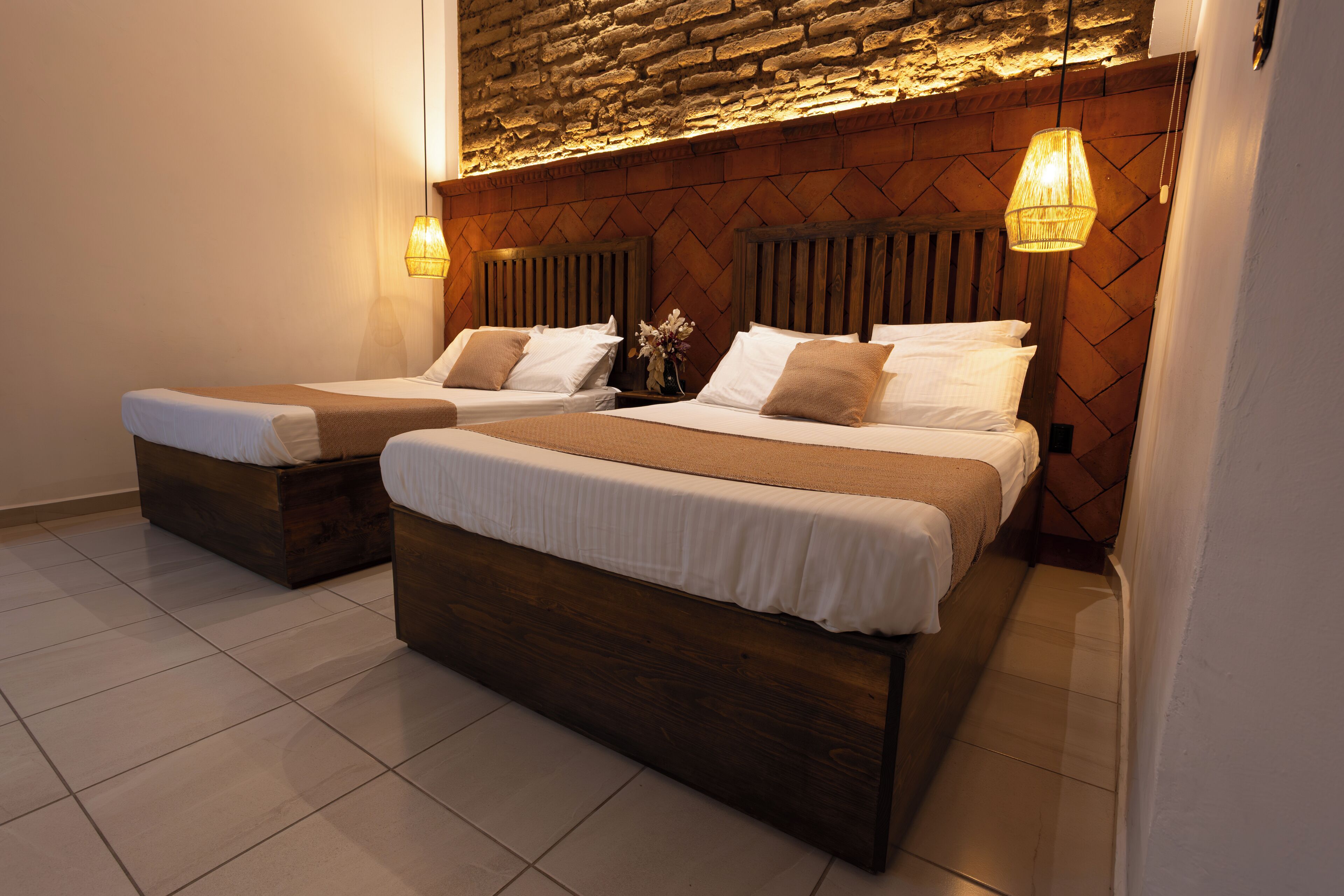 Una habitación de hotel con dos camas, cabeceros de madera y una pared de piedra.