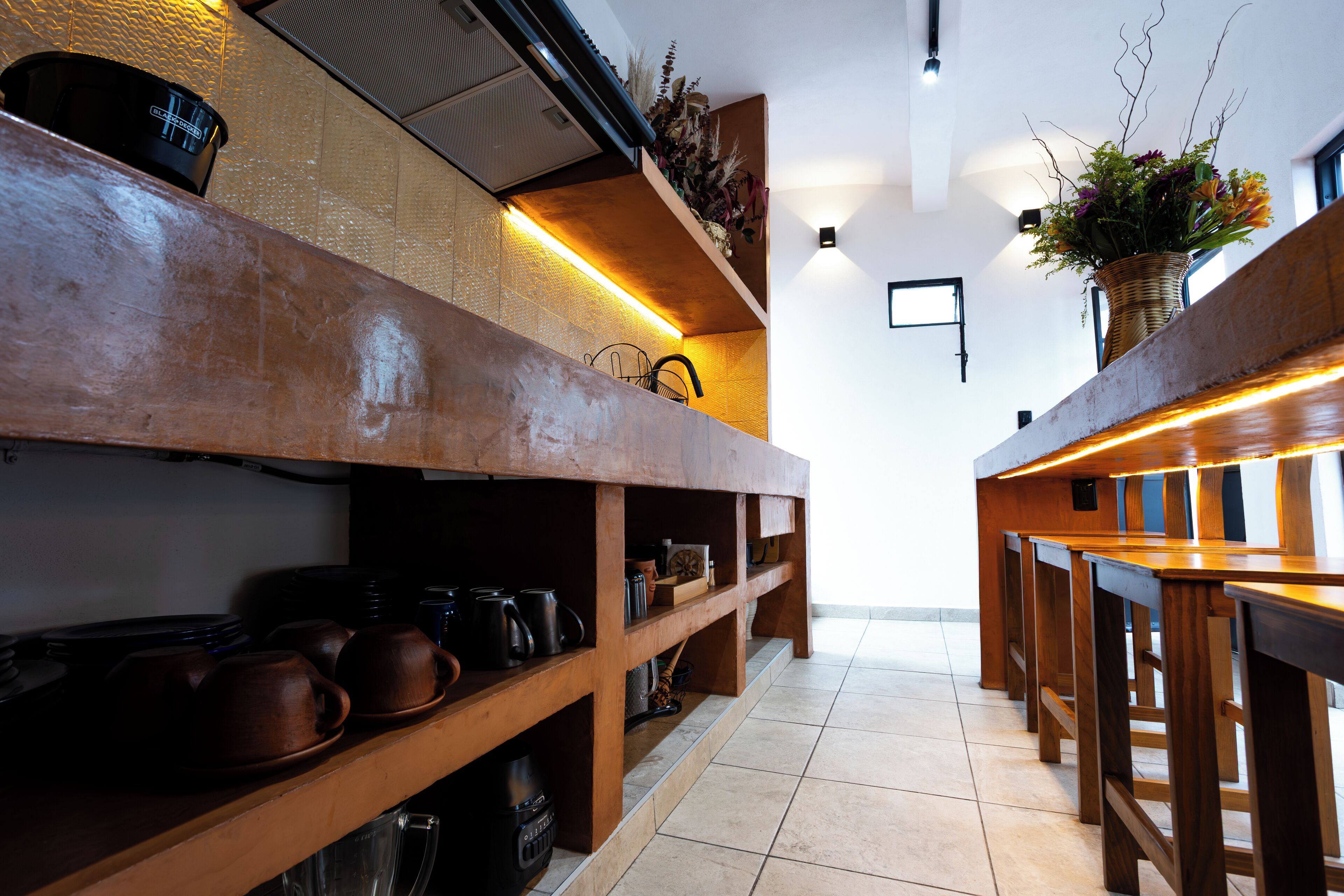 A kitchen with wooden shelves, a coffee machine, and a hanging plant.