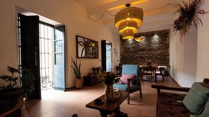 A spacious living area with a large window, a stone wall, a dining table, and a sofa. - Casa Sofi Oaxaca (Oaxaca)