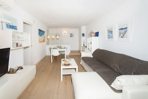 A modern living room with a sofa, a dining table, and a TV. - WELCS APARTAMENTO 165 PDA con piscina (Platja d´Aro)