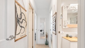 A hallway with framed artwork, a wooden floor, and a view into a bedroom. - WELCS APARTAMENTO 165 PDA con piscina (Platja d´Aro)