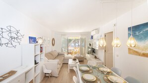 A modern living room with a sofa, dining table set for four, and a kitchen area visible in the background. - WELCS APARTAMENTO 165 PDA con piscina (Platja d´Aro)