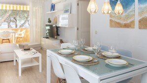 A dining area with a glass table set for six, white chairs, and pendant lights. - WELCS APARTAMENTO 165 PDA con piscina (Platja d´Aro)