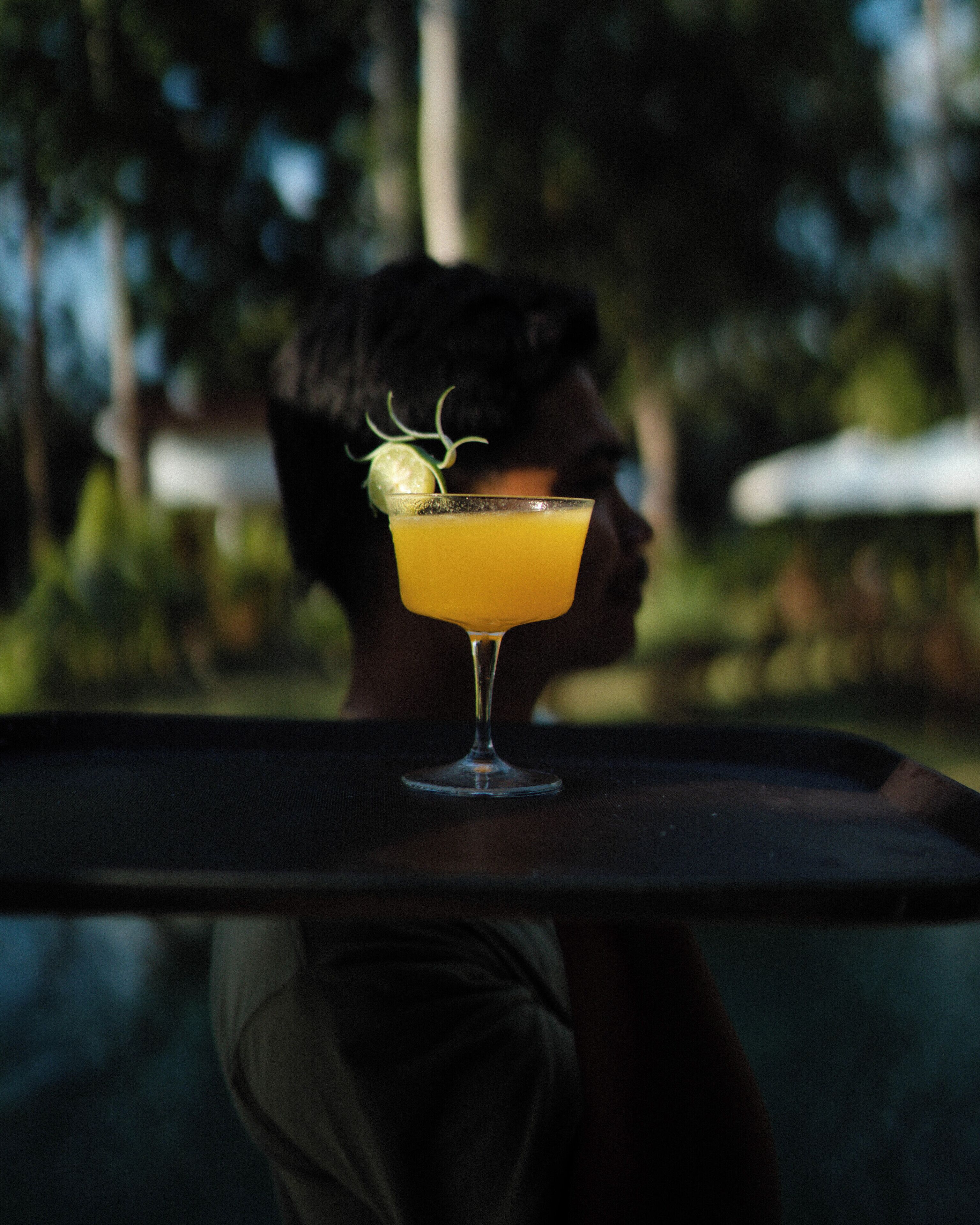 A cocktail glass with a lime garnish on a table.