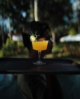 A cocktail glass with a lime garnish on a table.