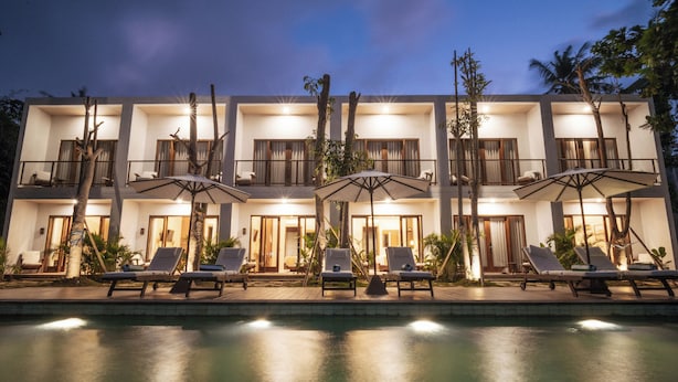 A modern hotel with a poolside lounge area, multiple balconies, and outdoor umbrellas. - Tika Lombok (Kuta)