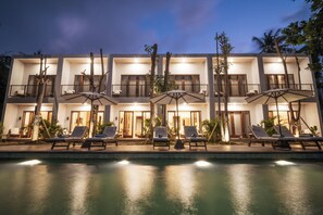 A modern hotel with a poolside lounge area, multiple balconies, and outdoor umbrellas. - Tika Lombok (Kuta)