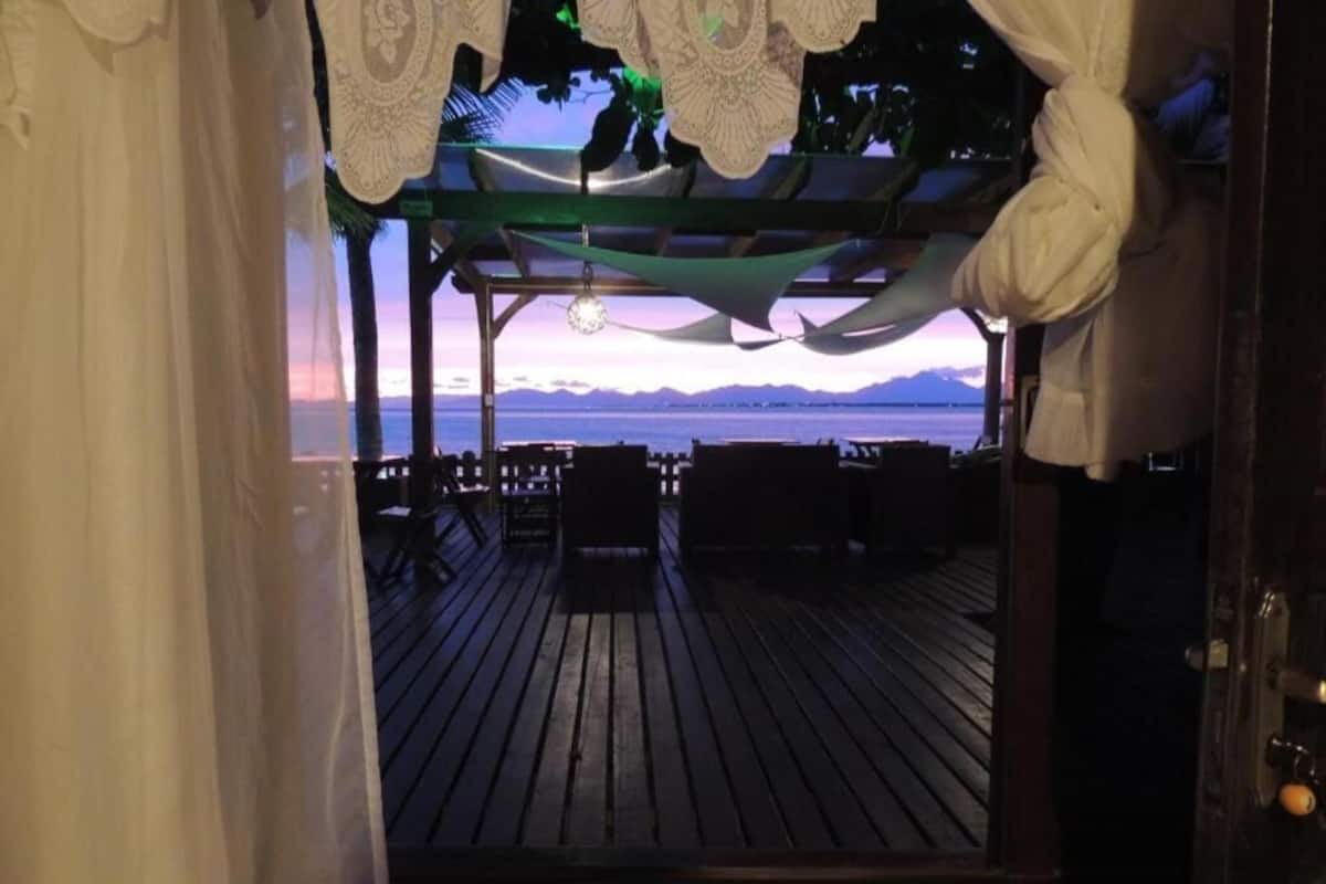 A wooden deck with chairs and a view of the sea at sunset.