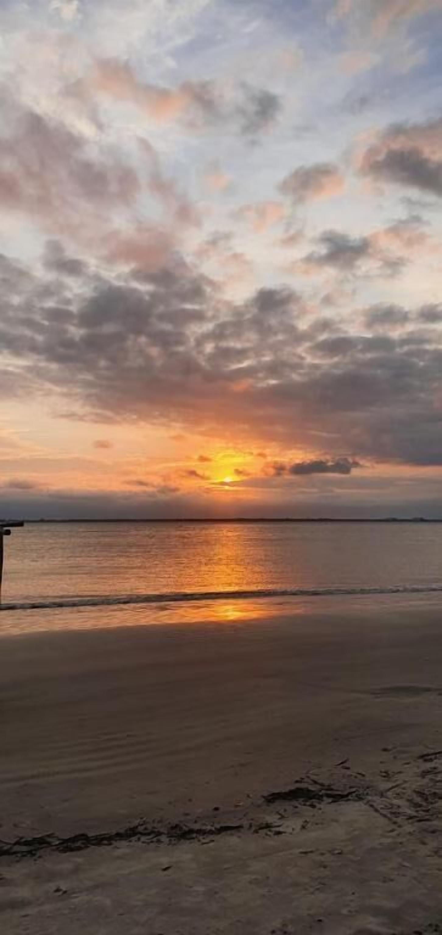 A beach with a sunset over the water.