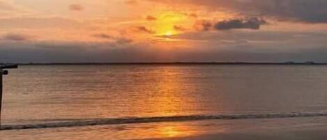 A beach with a sunset over the water.