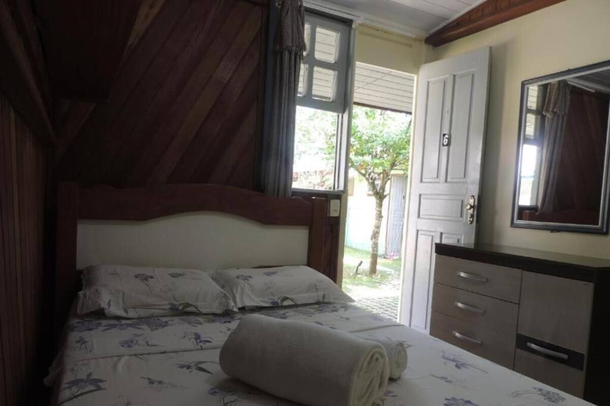 A bedroom with a bed, a window, a door, and a mirror.