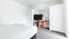 A hotel room with a bed, a desk with a television, and a wardrobe. - Unanderra Hotel  (Unanderra)