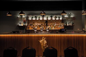 A bar area with wooden paneling, multiple hanging pendant lights, and shelves stocked with bottles. - Unanderra Hotel  (Unanderra)
