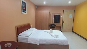 A hotel room with a bed, a desk, a chair, a wardrobe, and a door. - Buddy Mansion (Bangkok)